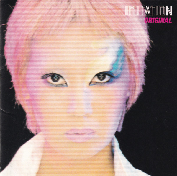 Photo of the band's singer with a makeup potentially inspired by Ziggy Stardust and probably other new wave aesthetics with neon colors. The singer's hair is also fluor pink. On the top right corner is the name of the band and the album.